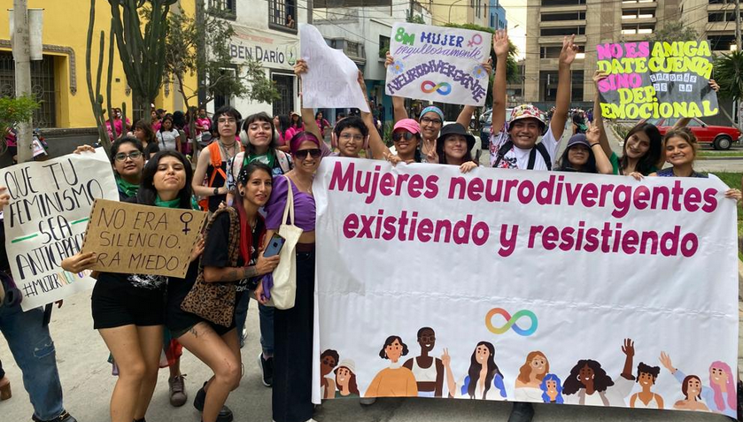 Foto de manifestantes neurodivergentes y banderolas con pancartas